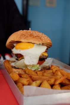 a hamburger with an egg on top and french fries