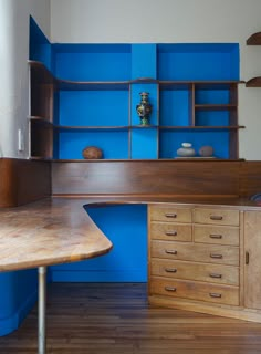 a wooden desk sitting in front of a blue book case on top of a hard wood floor