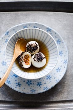 three deviled eggs with sprinkles in a blue and white bowl next to a wooden spoon