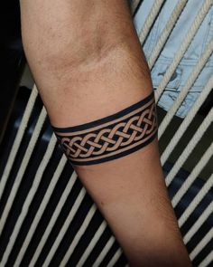 a man's arm with a tattoo on it and a black band around the wrist