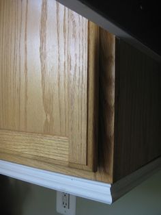 the corner of a kitchen cabinet that has been painted white and is being replaced with wood