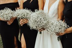 three bridesmaids in black dresses holding bouquets of baby's breath flowers