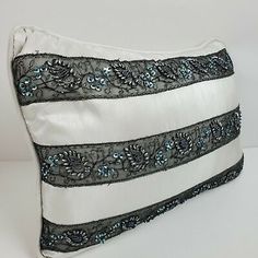 a white and black pillow with blue sequins on the side, sitting on a table