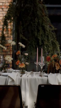 the table is set with white linens and flowers in vases on each side