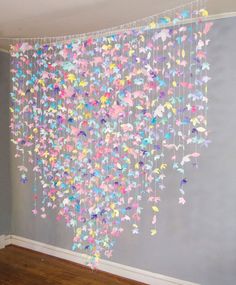 a room with a wall hanging made out of paper butterflies and streamers on the ceiling