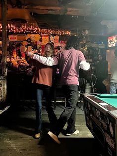 two people are playing pool in a bar