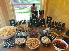 a table topped with lots of food and desserts next to a sign that says bunco babes