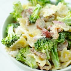 a bowl filled with pasta and broccoli on top of a white tablecloth