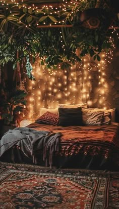 a bed covered in lots of lights next to a tree filled with green leaves and branches