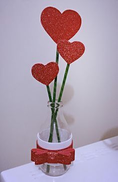 three red hearts are in a vase with water