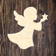 a wooden cutout of an angel holding a star on top of a wood background