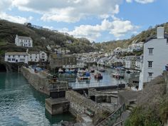 boats are docked in the water near buildings and cliffs on a hill side with blue sky