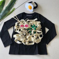 a black shirt with white and green designs on it next to a flower headband