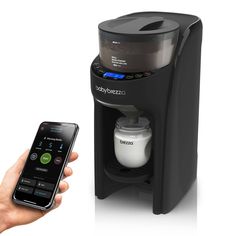 a person holding a cell phone next to a coffee maker and water dispenser