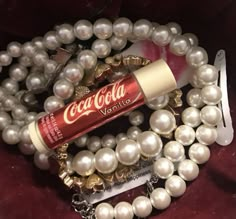 a bottle of coca cola sitting on top of a bracelet with pearls and other jewelry