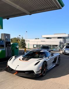 a white sports car parked in front of a gas station