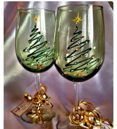 two wine glasses sitting on top of a table covered in gold ribbon and christmas decorations