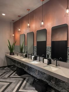 a row of sinks in a public restroom with mirrors and lights on the wall above them