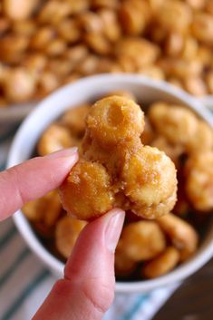 a person is holding some food up to their face in front of the bowl full of nuts