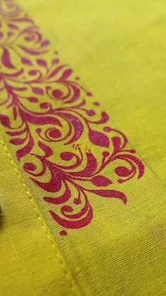 a yellow and red table cloth with an intricate design on the edge, next to a pair of scissors