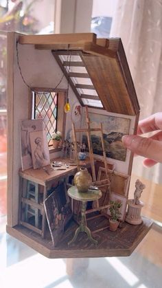 a miniature dollhouse with furniture and pictures on the wall in it's display case