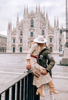 a man and woman standing next to each other in front of a building with tall spires