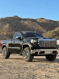 a black truck is parked in the dirt