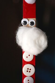 a close up of a wooden stick with buttons and santa clause on it's face