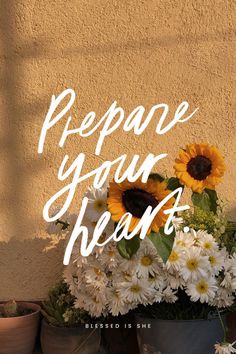 a vase filled with white and yellow flowers next to a wall that says prepare your heart