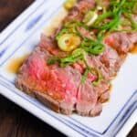 a white plate topped with meat and veggies on top of a wooden table