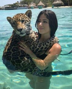 a woman is holding a large leopard in the water with her arms wrapped around her