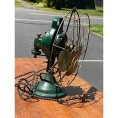 an old fashioned green fan sitting on top of a wooden table