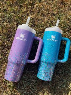 two purple and blue coffee mugs sitting on the grass