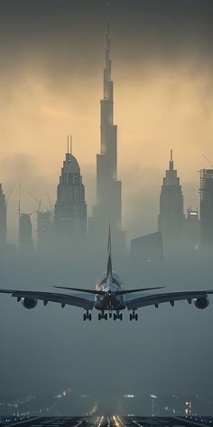 an airplane is taking off from the runway in front of a city skyline on a foggy day