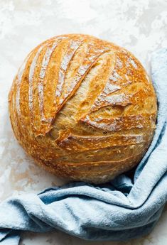 a round loaf of bread sitting on top of a blue towel next to a piece of cloth