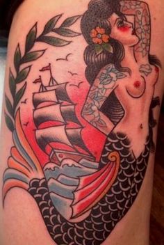 a woman with a tattoo on her arm is sitting in front of a fish and ship