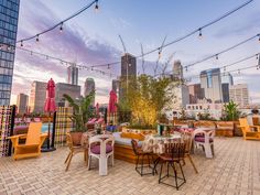 an outdoor dining area with tables and chairs, lights strung over the cityscape