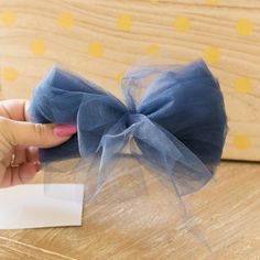 a hand holding a blue bow on top of a wooden table