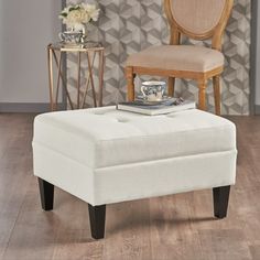 a white ottoman sitting on top of a hard wood floor next to a chair and table