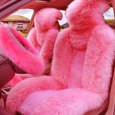 two pink teddy bears sitting in the back seat of a car with furry seats covers