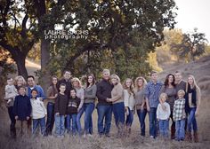 a large group of people are posing for a photo in the grass with trees behind them