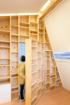 there is a person standing in the open bookcases that are made out of wood