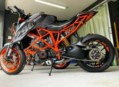 an orange and black motorcycle parked in a garage