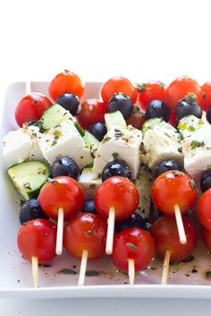 the skewers have tomatoes, cucumbers and black olives on them