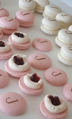 pink and white macaroons are arranged on a table with the letters j in them