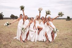 a group of bridesmaids in white dresses holding bouquets and posing for the camera