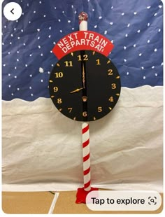 a clock that is on top of a pole with a candy cane in front of it