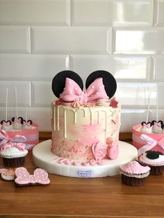 a minnie mouse cake and cupcakes on a table