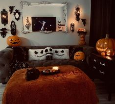 a living room decorated for halloween with pumpkins on the couch and candles lit up