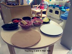 a table with bowls and plates on it in a play kitchen area for children to eat